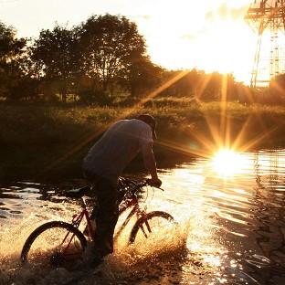 A man cycles through floodwater as torrential downpours cause flash floods in Hebburn (APl)