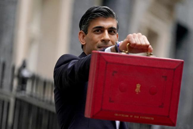 Chancellor of the Exchequer Rishi Sunak holds his ministerial 'Red Box' as he stands with his ministerial team and Parliamentary Private Secretaries, outside 11 Downing Street, London, before delivering his Budget to the House of Commons. Picture