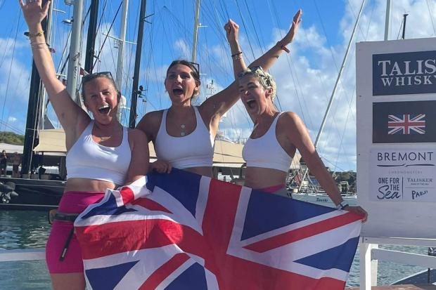 British rowers Abby Johnston, Charlotte Irving and Kat Cordiner celebrate with a British flag on the dock after smashing the world record.