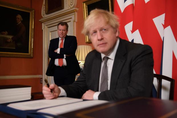 UK chief trade negotiator, David Frost looks on as Prime Minister Boris Johnson signs the EU-UK Trade and Cooperation Agreement at 10 Downing Street, Westminster