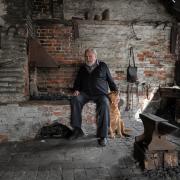 Reg Foster pictured inside the smithy with dog Amber